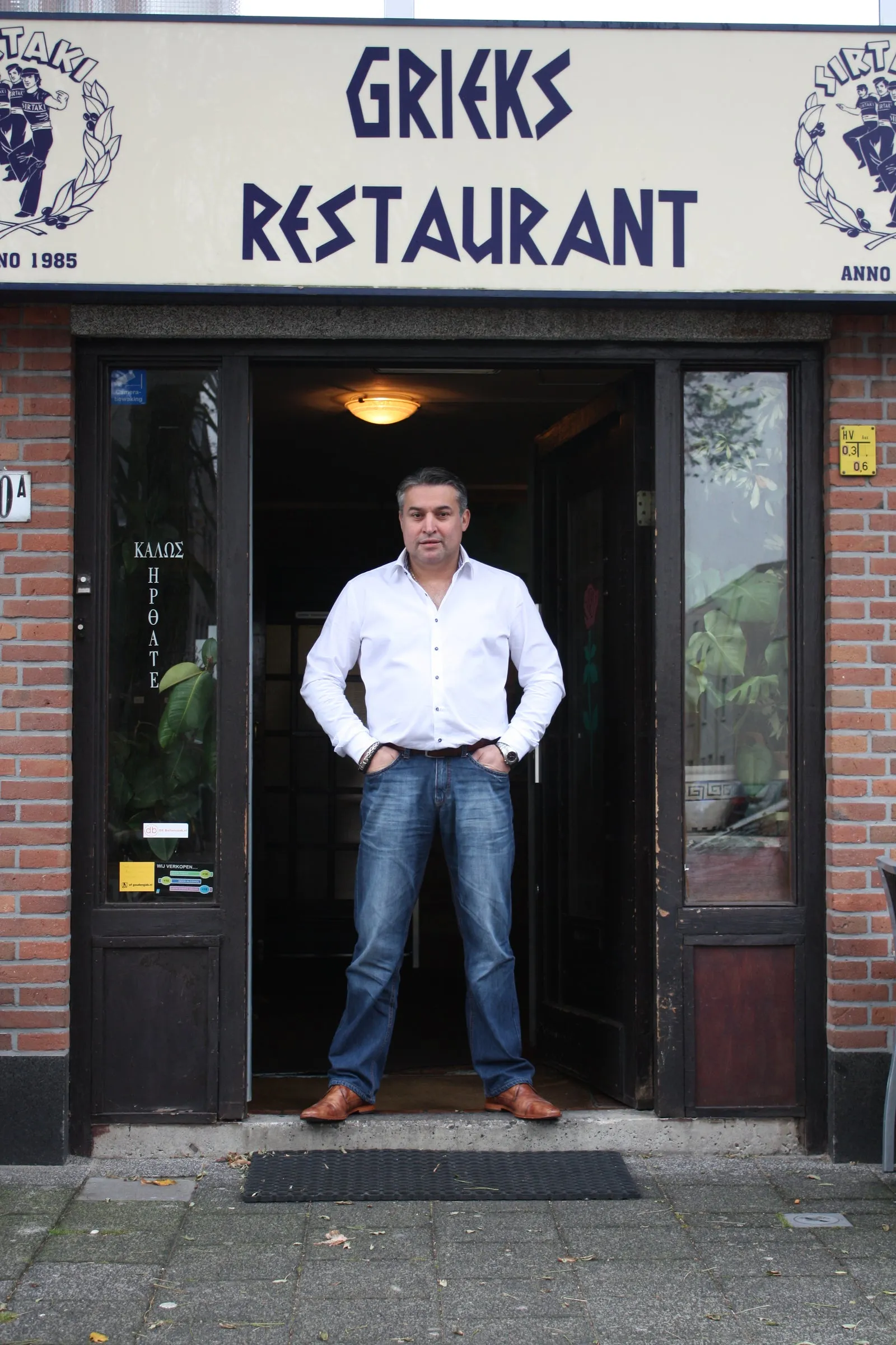 Makis Sirtaki, gastheer en eigenaar, in de deuropening van Grieks Restaurant Sirtaki Den Haag